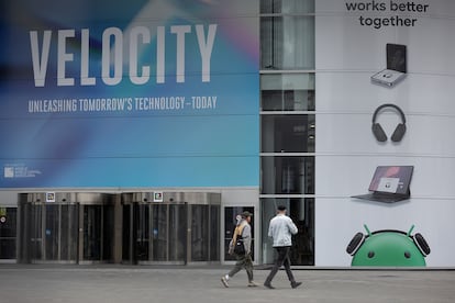 Dos personas caminan este domingo junto a una gran carta publicitaria en el rectinto de la Fira Gran Via donde se cebra al lunes el Mobile World Congress.