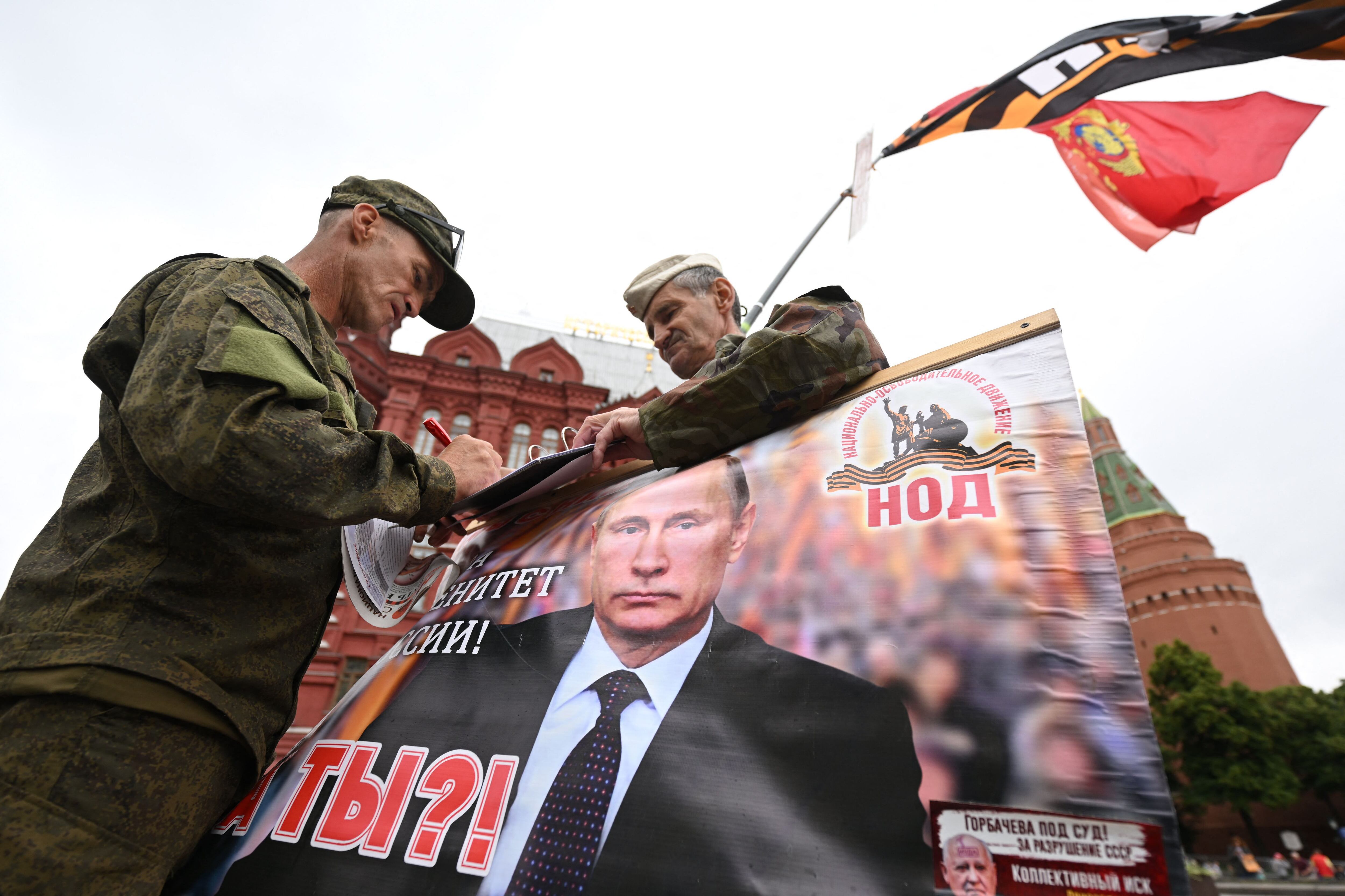 Dos hombres sostienen una imagen de Vladímir Putin en la Plaza Roja de Moscú, el sábado. 