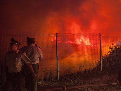 Dois policiais controlam uma área perto das colinas de Valparaíso, onde o fogo devastou 260 hectares.