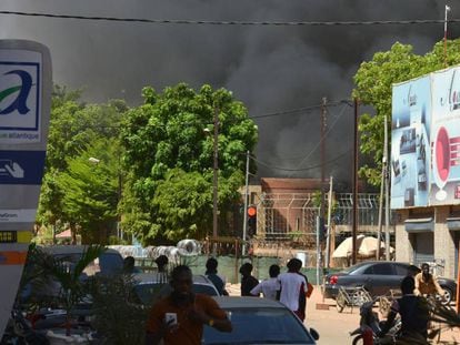 Varias personas observan una cortina de humo negro tras un ataque múltiple en Uagadugú, la capital de Burkina Faso.
