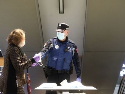 Un policía municipal reparte mascarillas en el acceso al intercambiador de Avenida de América.