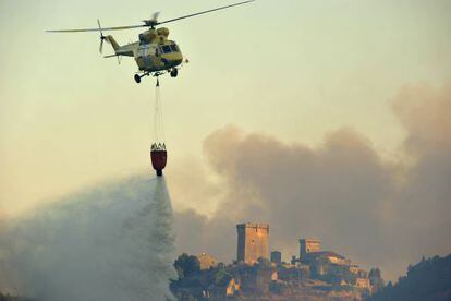 Un helicóptero descarga agua con el castillo de Monterrei al fondo