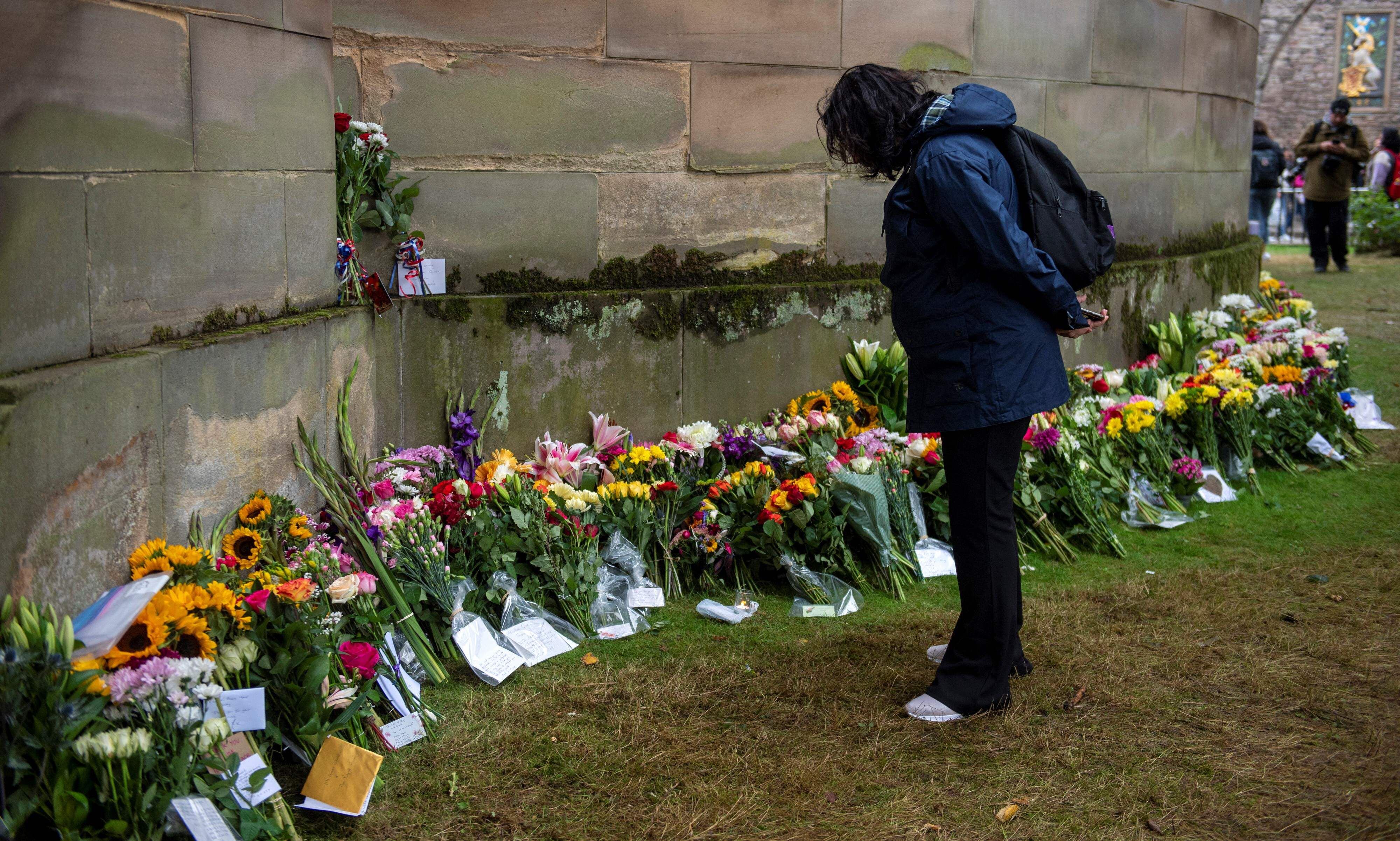 Una mujer observa las flores colocadas a los pies del palacio de Holyrood House, en Edimburgo, este viernes.