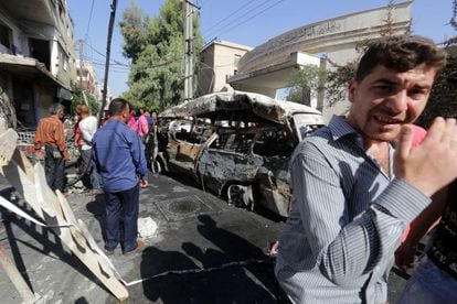 Varias personas observan la camioneta bomba con la que se ha efectuado el atentado en el barrio druso de Jaramana.