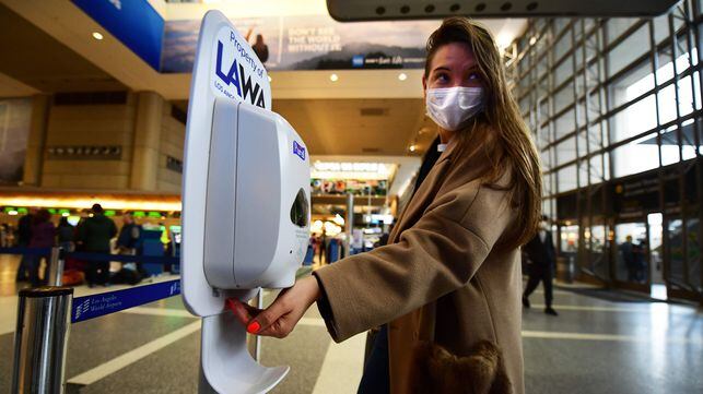 A woman wearing a facemask uses hand sanitizer on arrival at Los Angeles International Airport on March 12, 2020, one day before a US flight travel ban hits 26 European countries amid ongoing precautions over the Coronavirus. - US President Donald Trump announced a shock 30-day ban on travel from mainland Europe over the coronavirus pandemic that has sparked unprecedented lockdowns, widespread panic and another financial market meltdown Thursday.The announcement came as China, where the outbreak that first emerged in December, showed a dramatic drop in new cases and claimed "the peak" of the epidemic had passed. (Photo by Frederic J. BROWN / AFP)