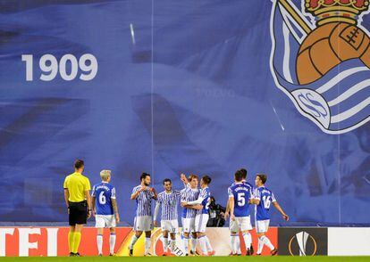 Jugadores de la Real Sociedad celebran un gol ante la lona que tapa las obras en el estadio de Anoeta.