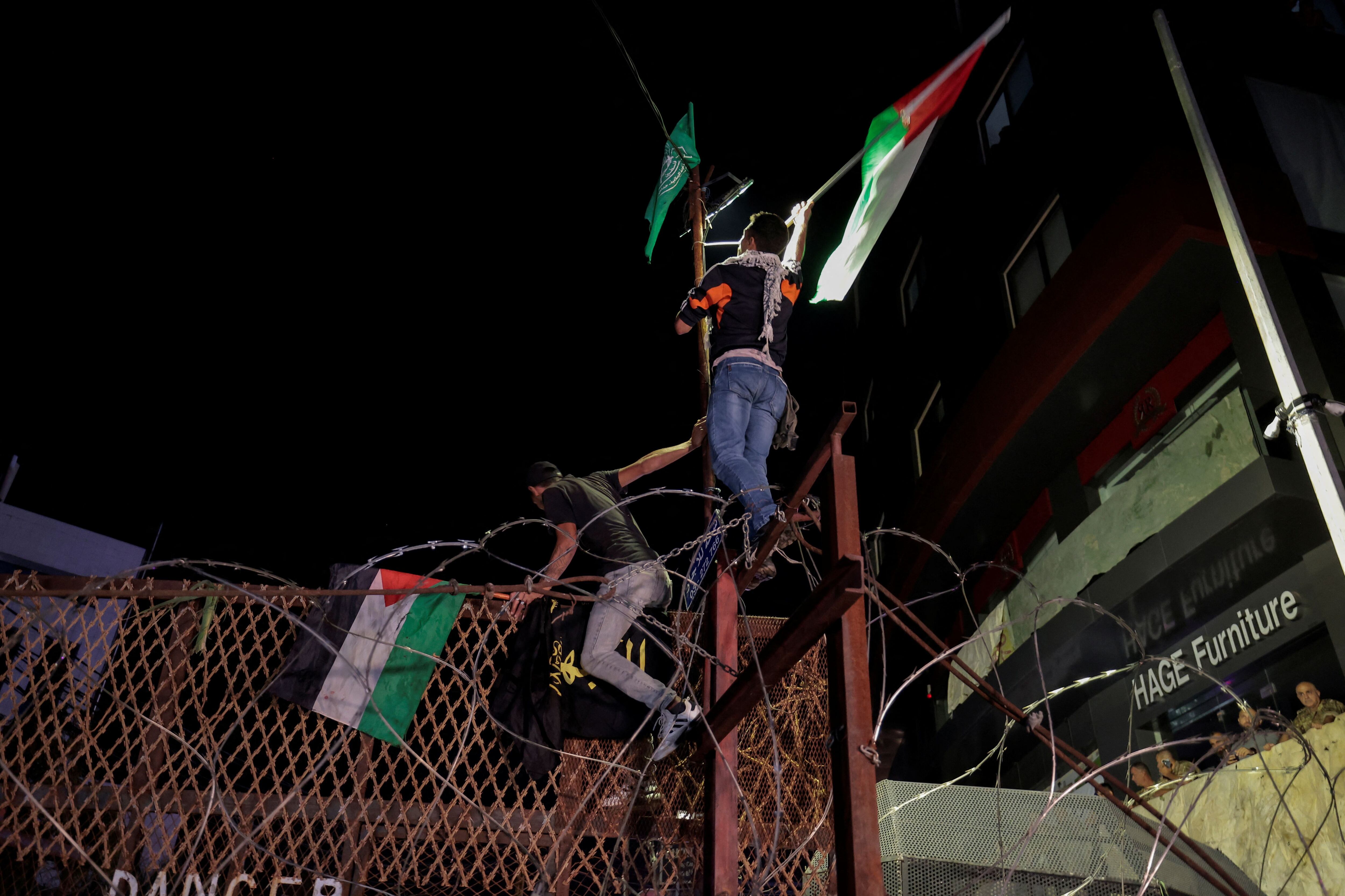 Dos manifestantes se encaraman a las vallas de la embajada estadounidense en Beirut, Líbano. 