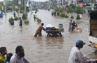 Viandantes paquistaníes cruzan una calle inundada después de las fuertes lluvias que han asolado Lahore.