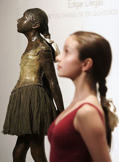 Una bailarina posa delante de la escultura de Degas.