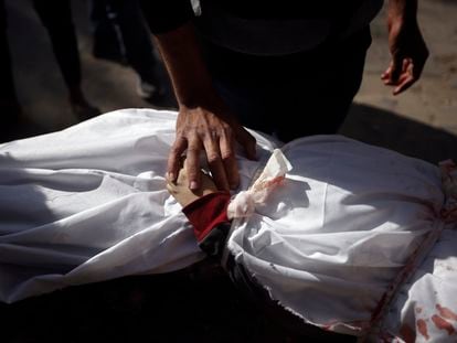 Un hombre toca la mano de un niño muerto en un bombardeo israelí sobre Jan Yunis en la franja de Gaza.