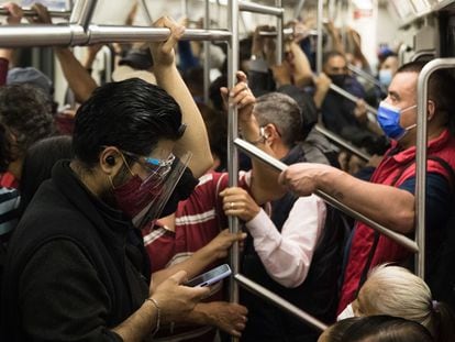 Un joven con careta y cubrebocas mira el celular en un vagón del metro de Ciudad de México.