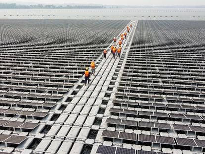 Empleados caminan por la plataforma que sostiene 144.000 paneles solares sobre el agua de la presa Sirindhorn, en Tailandia, el 8 de abril.