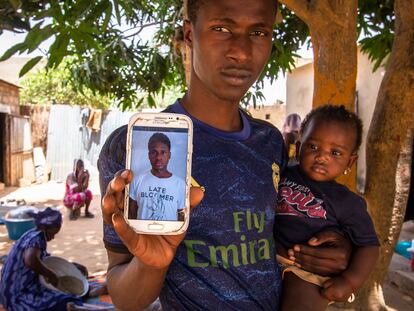 Said Fall muestra un retrato de su hermano pequeño Mohamed, que se encuentra en un centro de acogida en Tenerife, mientras sostiene en brazos a su sobrina Mame Diarra.