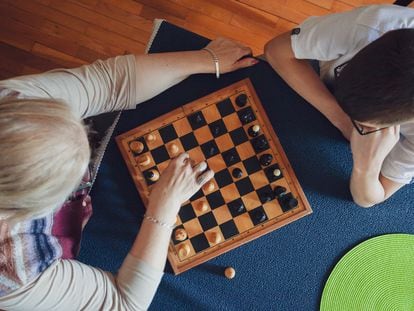 Una abuela enseñando a su nieto a jugar al ajedrez.