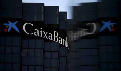 El logo de CaixaBank reflectit en el vidre d'un cartell publicitari, a Barcelona.