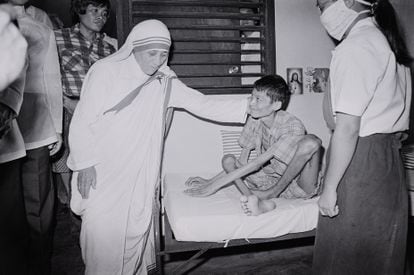Teresa of Calcutta caresses a sick person, who suffers from polio, in Manila, on November 27, 1982. 