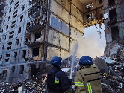 Dos bomberos trabajan para extinguir un fuego en un edificio residencial dañado por un misil ruso, este domingo en Zaporiyia.