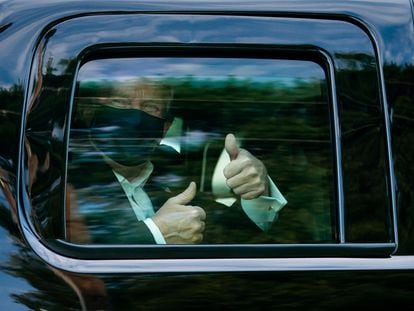 El presidente Donald Trump saluda desde el coche tras salir del hospital militar.