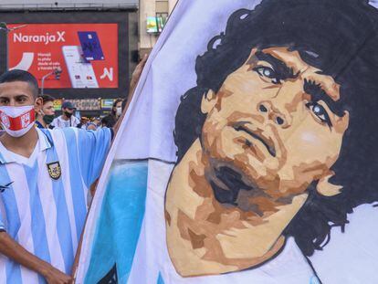 Un aficionado argentino sujeta una pancarta con el rostro de Diego Armando Maradona, que falleció ayer y sumió a la nación en el luto.