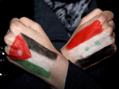 Un sirio se manifiesta en Amm&aacute;n con las banderas de Jordania (izquierda) y Siria pintadas en las manos.