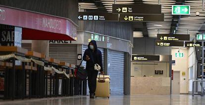 Un pasajero camina por el aeropuerto de Barajas entre tiendas y bares cerrados