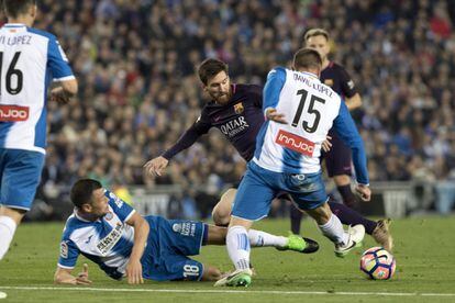 El delantero argentino del FC Barcelona Leo Messi disputa el balón con David López (d) y Javi Fuego (i), del RCD Espanyol.
