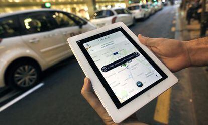Un usuario de Uber consulta la aplicaci&oacute;n ante una parada de taxis en el centro de Valencia.