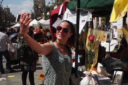 Una joven, en la Rambla Nova de Tarragona, se toma una fotografía mientras sujeta una rosa.