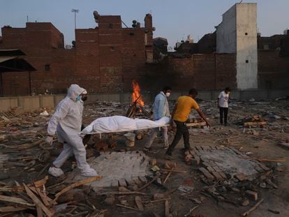 Voluntarios y familiares trasladan el cadáver de una víctima de la covid-19 para su cremación en Nueva Delhi, el pasado día 11.