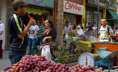 Un vendedor de uvas ambulante ofrece su mercancía con un micrófono en una de las calles comerciales de Medellín.