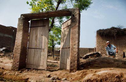 Un hombre permanece sentado enfrente de la puerta de su casa, derruida por las inundaciones en la localidad de Adiel Khan, a las afueras de Peshawar.