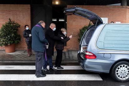 El cura José Luis Sáenz oficia la última oración a una víctima del coronavirus, un exboxeador. Su mujer rocía agua bendita sobre su ataúd, este lunes, en el cementerio Sur de Madrid.