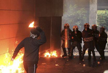 Un manifestante sostiene un cóctel molotov a las puertas ministerio de Finanzas griego delante de varios policías antidisturbios durante una huelga general convocada por los sindicatos hoy, miércoles, 15 de diciembre de 2010 en Atenas (Grecia), en contra de las medidas de austeridad proyectadas por el Gobierno griego.