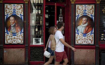 Una pareja pasea delante de un bar por una calle del Barrio de las Letras, en Madrid.   