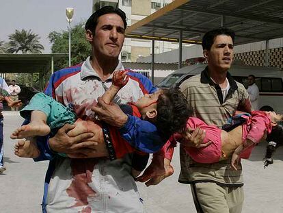 Dos iraquíes corren con unos niños heridos en brazos para llevarles al hospital en Ciudad Sáder, en Bagdad.