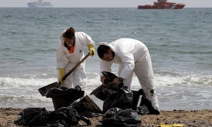 Operarios de limpieza del Ayuntramiento de Valencia recogen "galletas" de chapapote producidas por un vertido de fuel en la playa de El Saler, en abril de 2014. EFE/