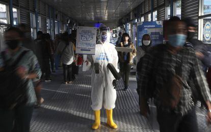 Un empleado sujeta una pancarta con información sobre el virus en una estación de autobuses de Yakarta.