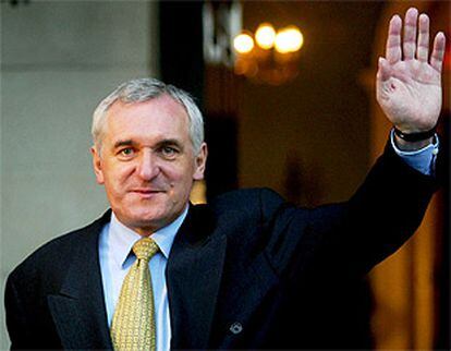 El primer ministro Bertie Ahern saluda a los periodistas en el castillo de Dublin después de haber sido elegido.