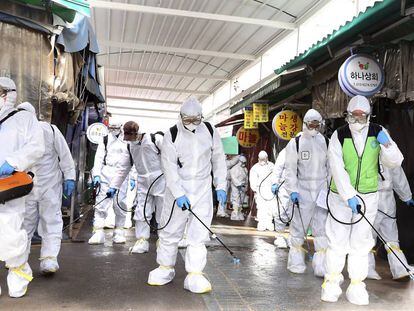 Trabajadores con trajes de protección desinfectan un mercado en Bupyeong, Corea del Sur, este lunes.