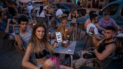 Un grupo de jóvenes muestran sus móviles en una terraza de la plaza de Cascorro, en Madrid. Ninguno de ellos compra periódicos ni sigue habitualmente los medios de comunicación.