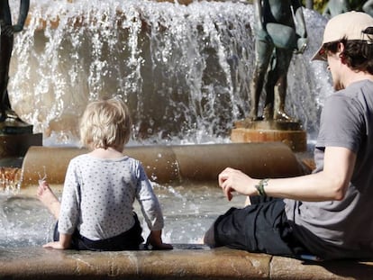 Un hombre y un ni&ntilde;o se refrescan en una fuente de Valencia. 