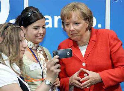 Dos estudiantes y Angela Merkel (derecha) observan un teléfono móvil durante un encuentro en Berlín dedicado al mercado laboral y las mujeres.