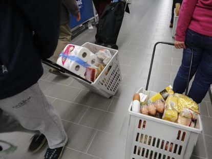 Varias personas haciendo la compra en un supermercado.
