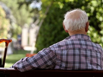Un pensionista sentado en un banco en un parque de Madrid.