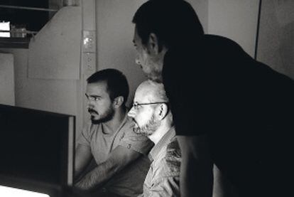 Juan José Campanella mira una pantalla de ordenador rodeado de dos colaboradores.