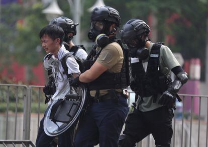 La policía detiene a un manifestante que intenta escapar en las manifestaciones ante la Politécnica. "Restablecer el orden" en Hong Kong "es la tarea más urgente", afirmó este lunes en Bangkok un portavoz del ministerio chino de Defensa, al referirse a la primera movilización de soldados chinos en las calles de la excolonia británica.