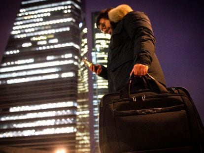 Un joven carga con su ordenador portátil en el distrito financiero de las cuatro torres, en Madrid.