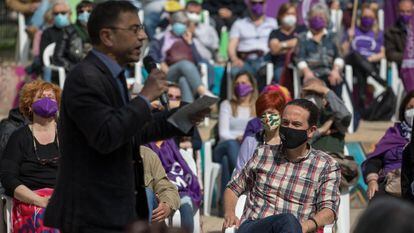 Juan Carlos Monedero participa en un mitin de Podemos en 2021, con Pablo iglesias sentado cerca de él.