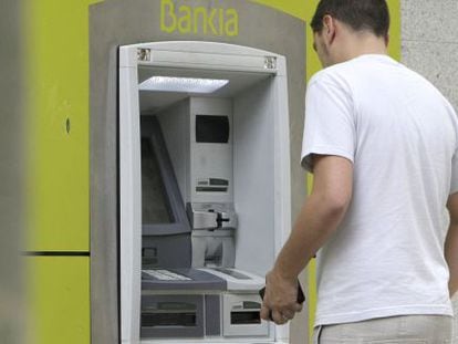 Un hombre saca dinero de un cajero automático de Bankia.