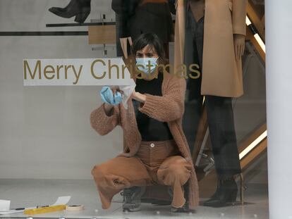 Una mujer prepara el escaparate de su tienda en el centro de Madrid para la campaña navideña.